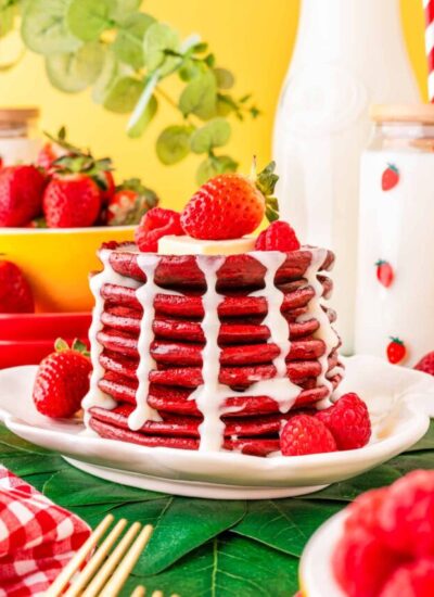 a stack of red velvet pancakes with cream cheese syrup topped with berries