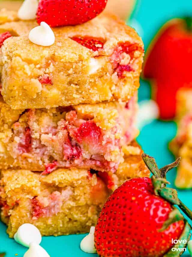 a stack of strawberry blondies next to some strawberries