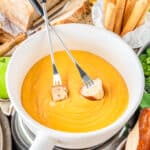 a bowl of cheese fondue with two fondue forks in it