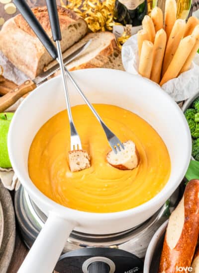 a bowl of cheese fondue with two fondue forks in it