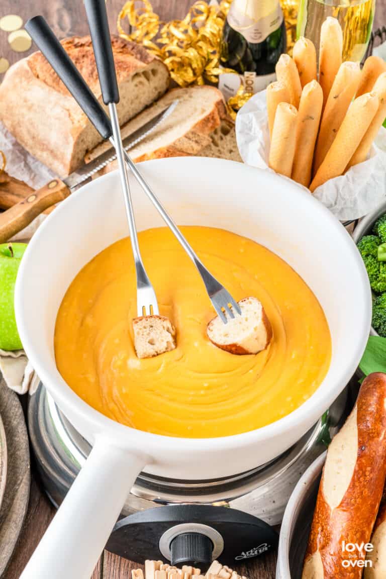 a bowl of cheese fondue with two fondue forks in it