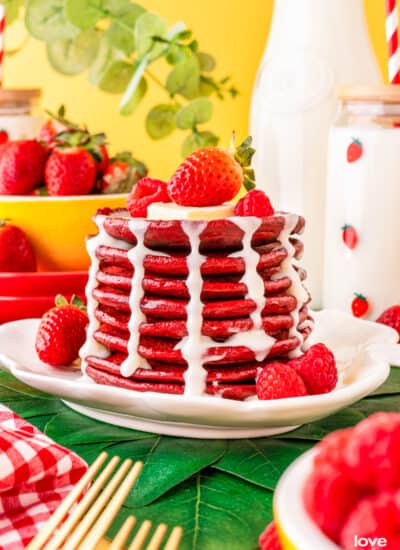 a stack of red velvet pancakes with cream cheese syrup topped with berries