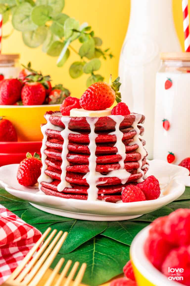 a stack of red velvet pancakes with cream cheese syrup topped with berries