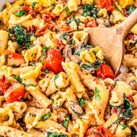 a wooden serving spoon scooping out some boursin cheese pasta