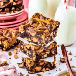 A stack of chocolate peanut butter brownies with milk bottles behind it.