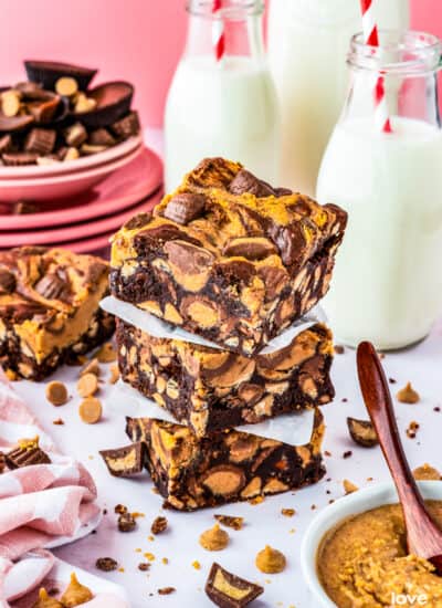 A stack of chocolate peanut butter brownies with milk bottles behind it.