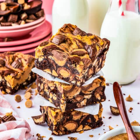 A stack of chocolate peanut butter brownies with milk bottles behind it.