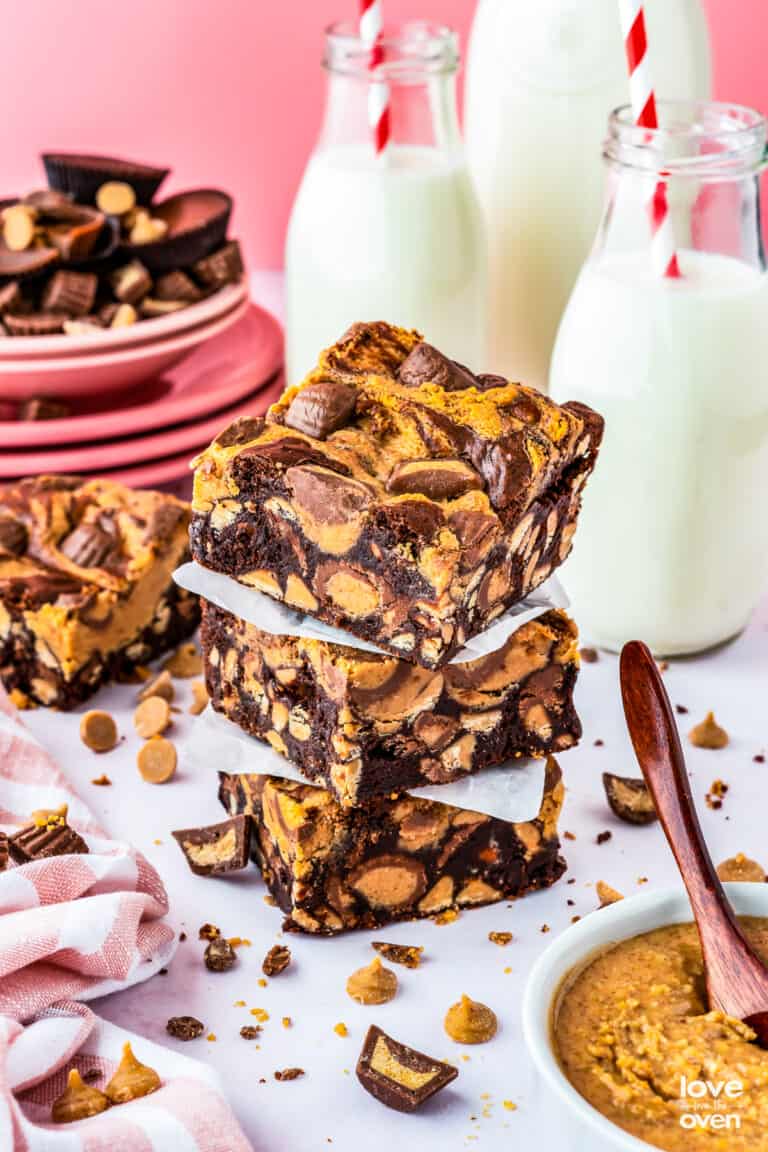 A stack of chocolate peanut butter brownies with milk bottles behind it.