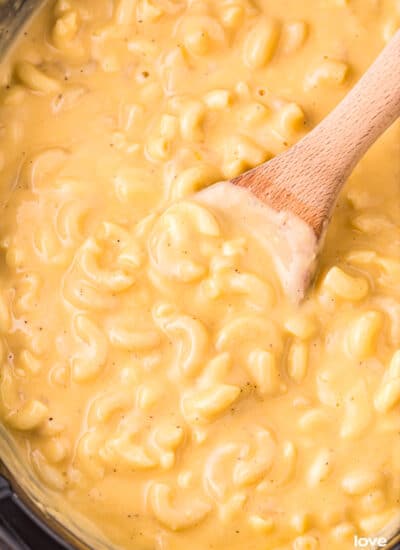 a wooden spoon in a crockpot of macaroni and cheese