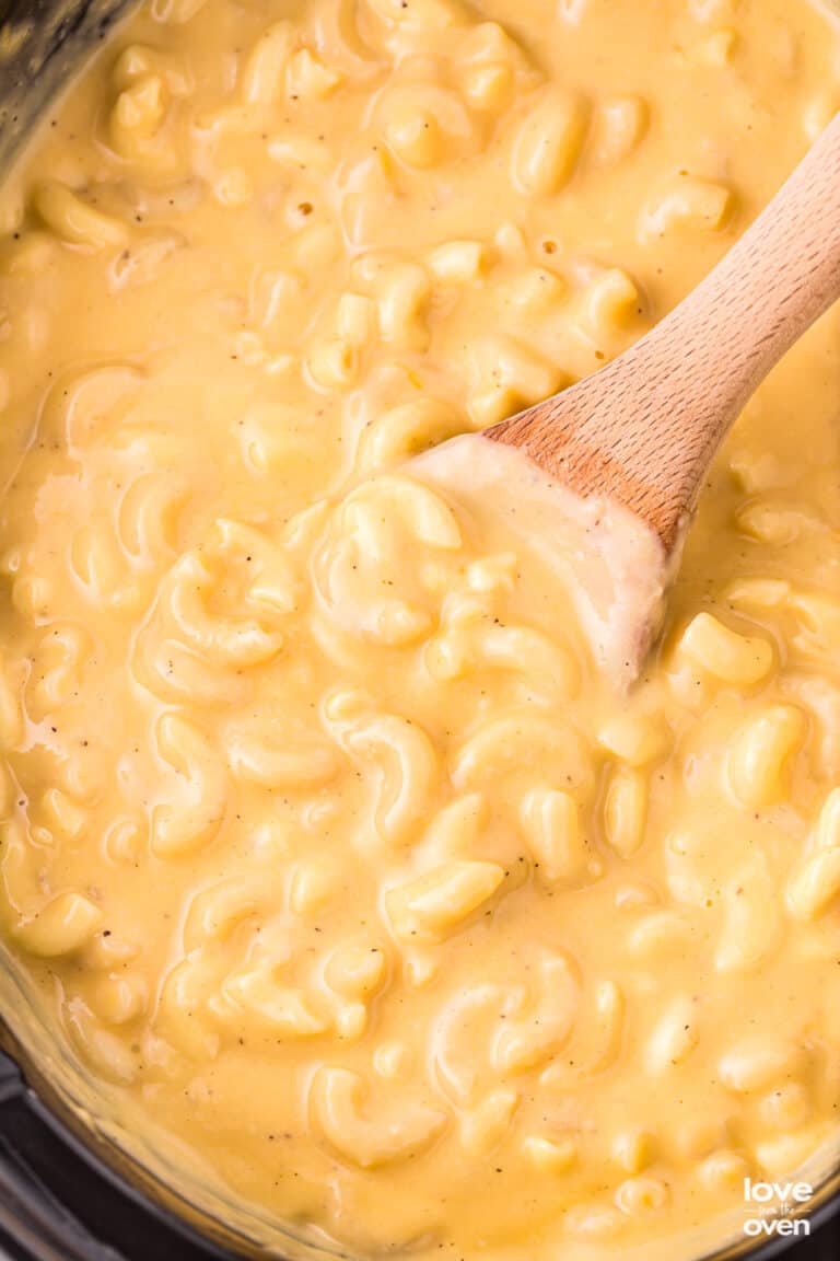a wooden spoon in a crockpot of macaroni and cheese