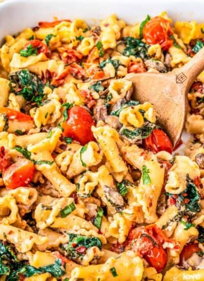 a wooden serving spoon scooping out some boursin cheese pasta