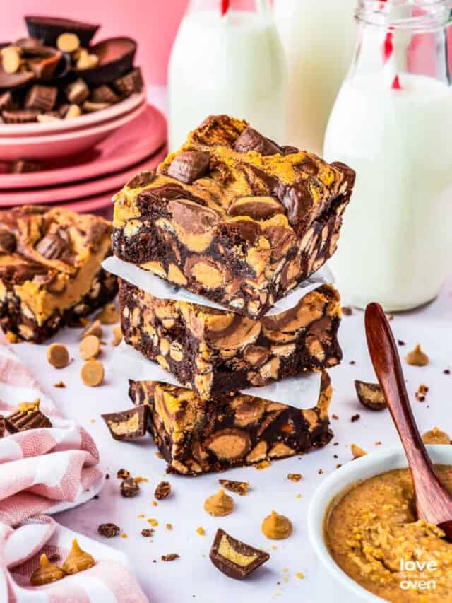 A stack of chocolate peanut butter brownies with milk bottles behind it.