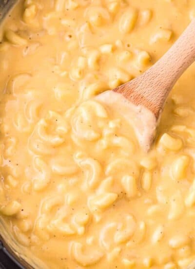 a wooden spoon in a crockpot of macaroni and cheese