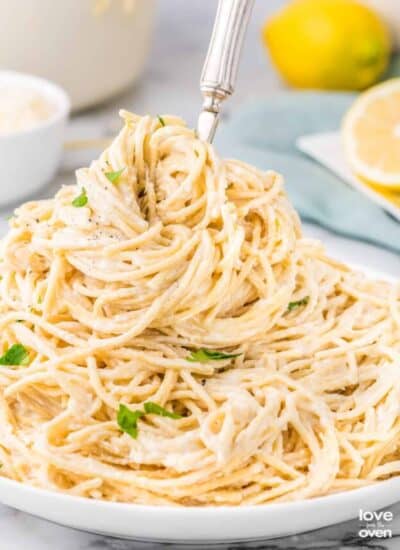 A plate of lemon butter pasta with a fork in it.