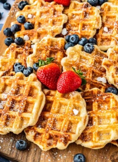 liege waffles on a wooden board decorated with fruit and sugar