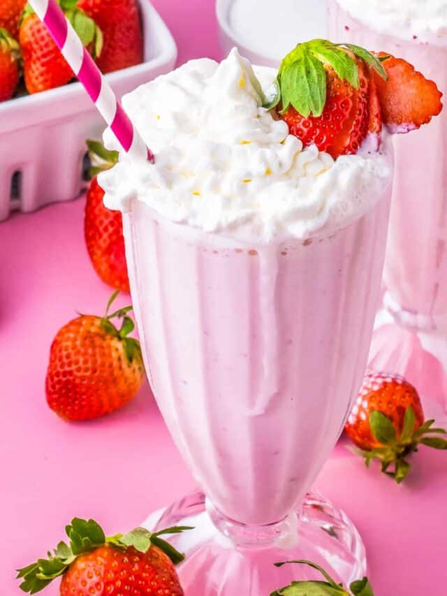 a strawberry milkshake with a strawberry on the edge of the glass and a pink and white straw