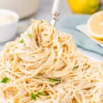A plate of lemon butter pasta with a fork in it.