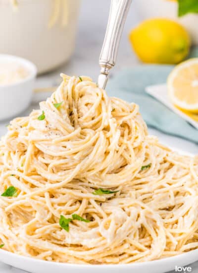 A plate of lemon butter pasta with a fork in it.