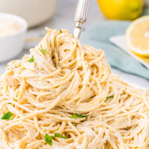 A plate of lemon butter pasta with a fork in it.