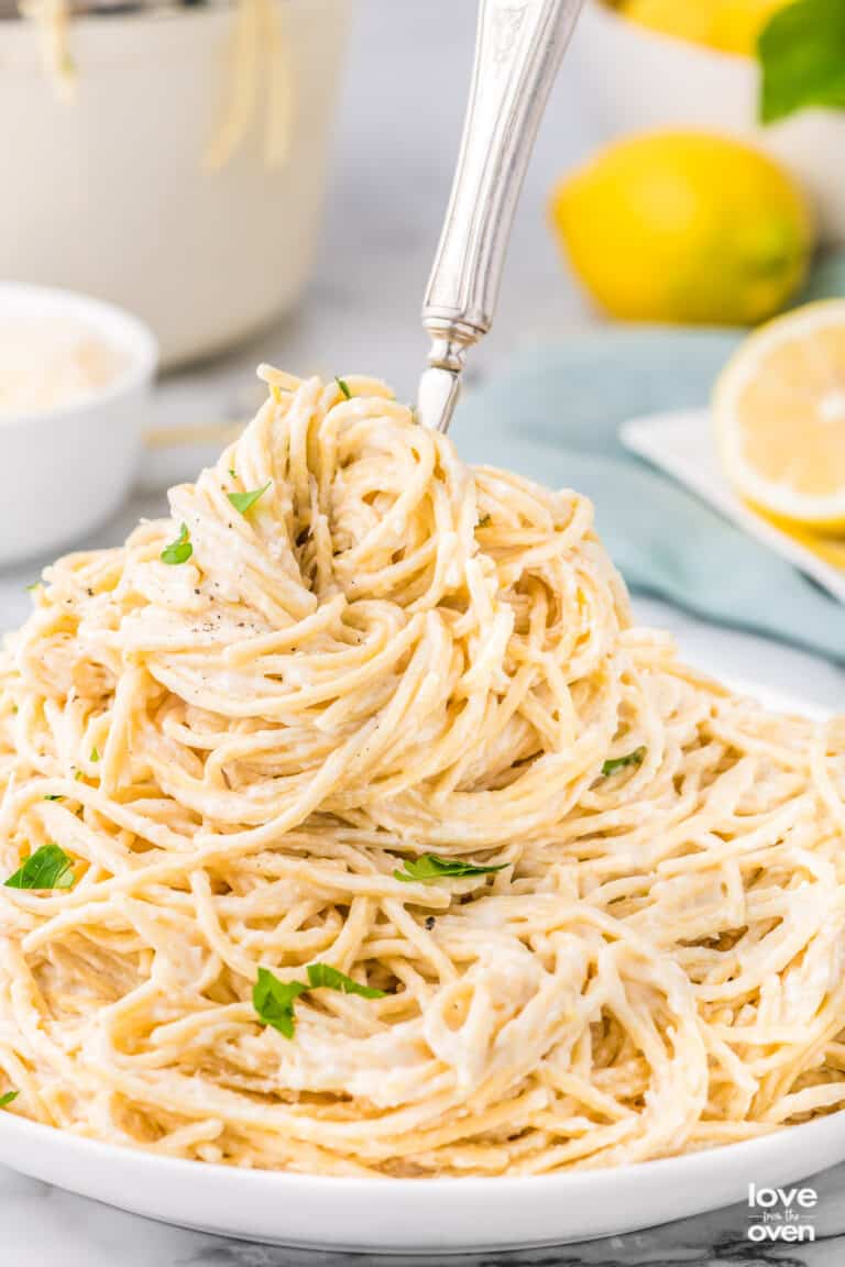 A plate of lemon butter pasta with a fork in it.