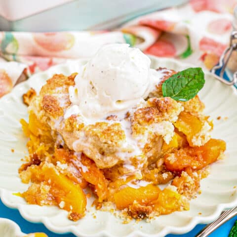 A plate with peach cobbler topped with ice cream