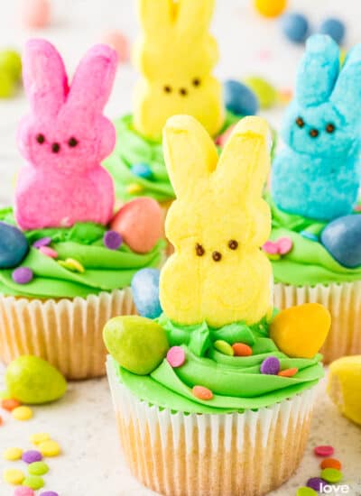 Cupcakes with green frosting and marshmallow bunny Peeps on top of them.