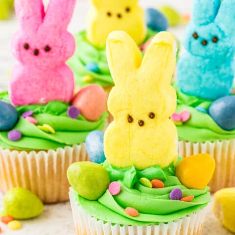 Cupcakes with green frosting and marshmallow bunny Peeps on top of them.