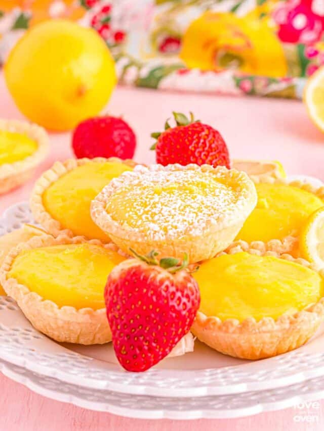 a plate full of lemon tarts with strawberries decorating the plate