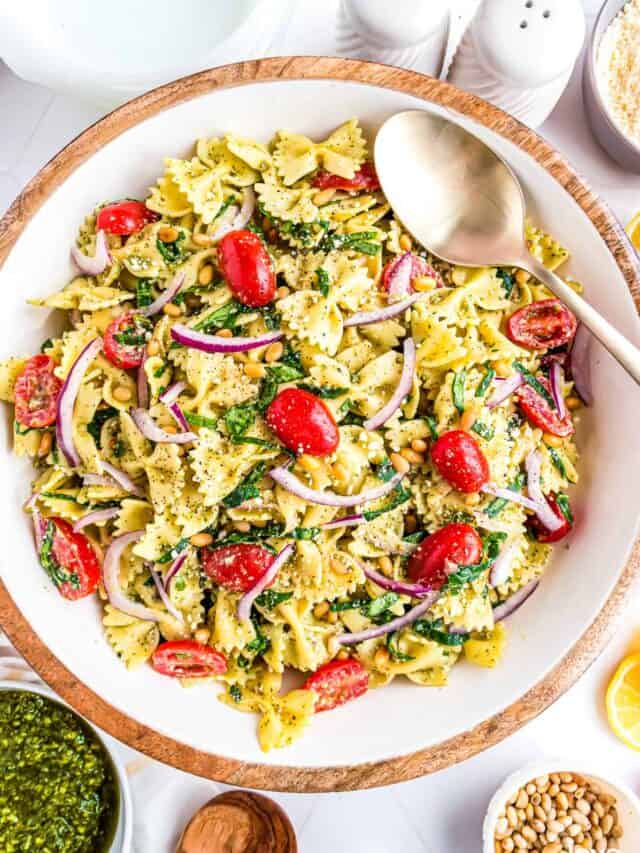 a large serving bowl full of pesto pasta salad
