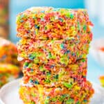 A stack of Fruity Pebbles Treats on a white plate with a blue background.