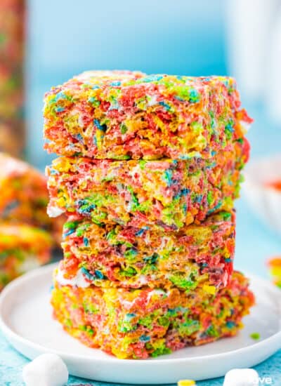 A stack of Fruity Pebbles Treats on a white plate with a blue background.