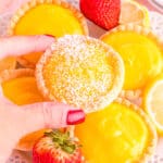 A hand grabbing one of many lemon tarts.