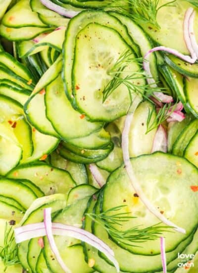 A close up photo of a cucumber salad with dill and onions.