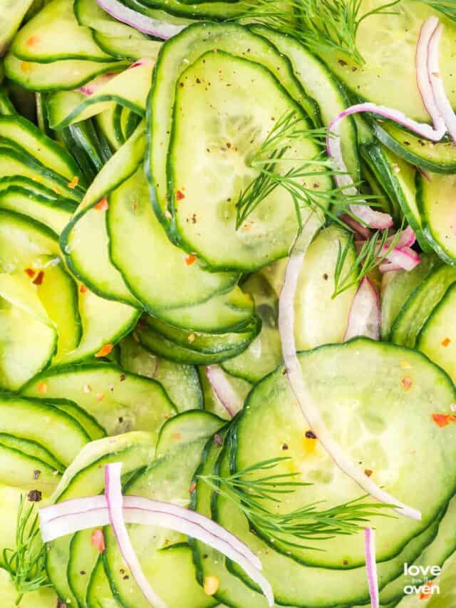 A close up photo of a cucumber salad with dill and onions.