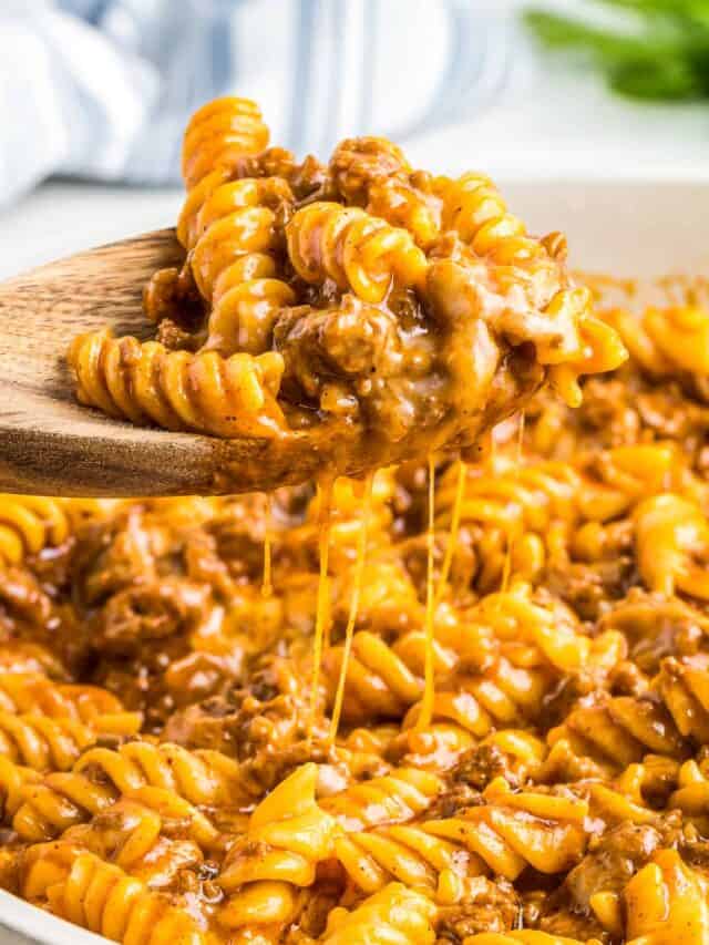 a wooden spoon taking a serving of enchilada pasta