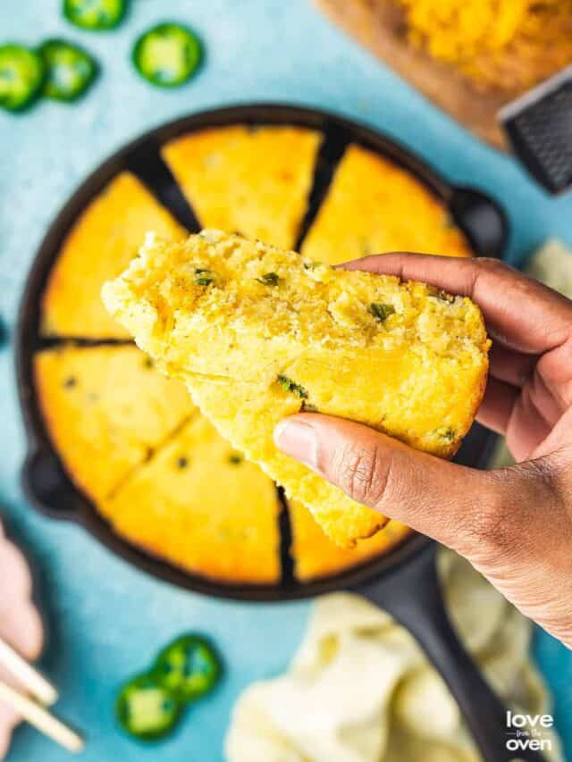 a hand holding a slice of jalapeno cornbread