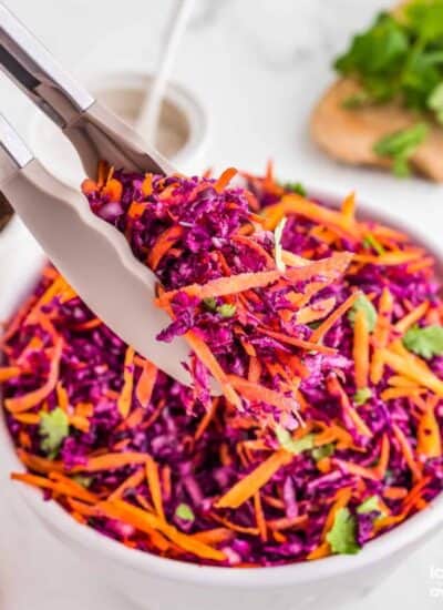 tongs holding a serving of red cabbage slaw