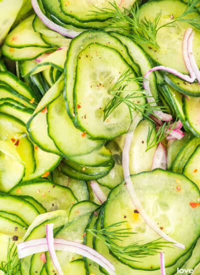 A close up photo of a cucumber salad with dill and onions.