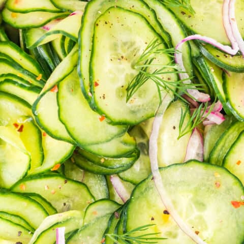 A close up photo of a cucumber salad with dill and onions.