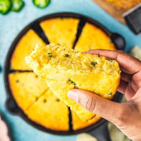 a hand holding a slice of jalapeno cornbread