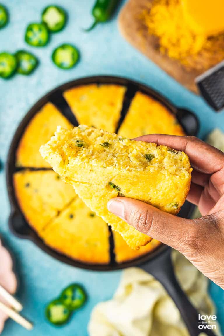 a hand holding a slice of jalapeno cornbread