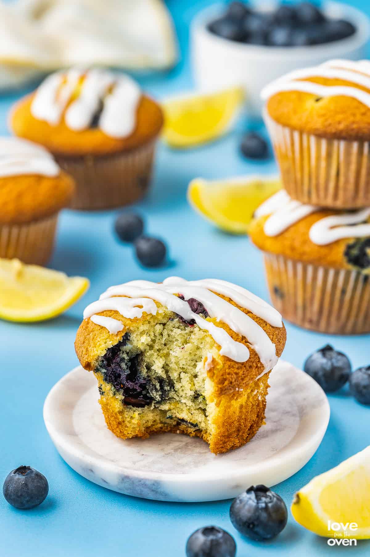 A lemon blueberry muffin on a blue background with a bite taken out of it