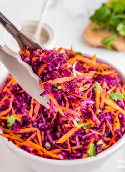 tongs holding a serving of red cabbage slaw