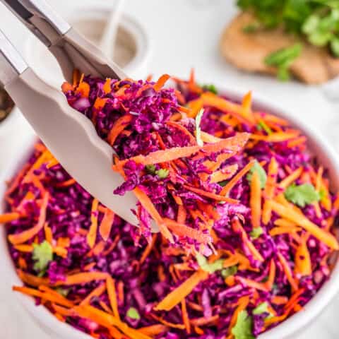 tongs holding a serving of red cabbage slaw