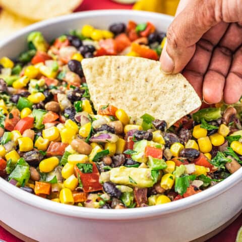 a hand holding a chip scooping up some cowboy caviar