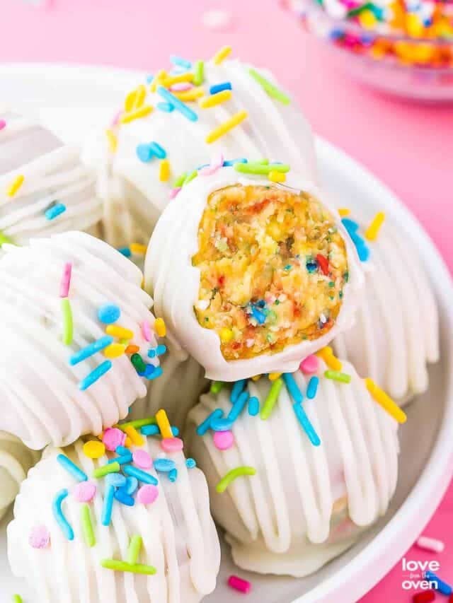 a bite taken out of a birthday cake pop on top of a pile of cake pops