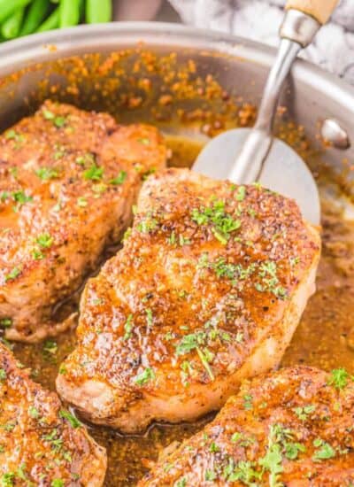 honey mustard pork chops on a skillet being flipped by a spatula