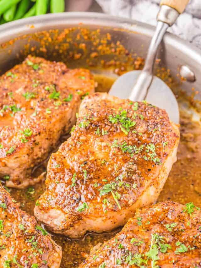 honey mustard pork chops on a skillet being flipped by a spatula