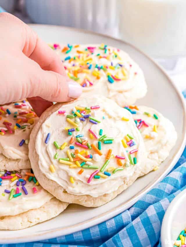 a hand lifting up a lofthouse sugar cookie
