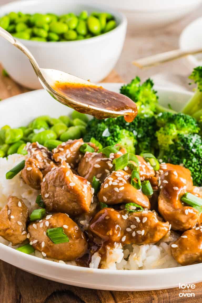 A spoon pouring teriyaki sauce over teriyaki chicken